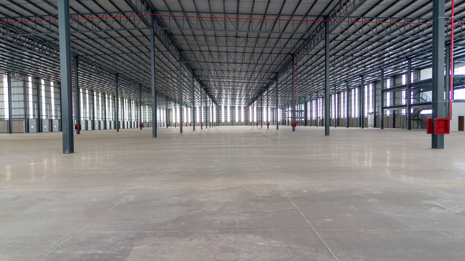 Interior de una nave industrial de gran claro, con la estructura metálica a la vista y la perspectiva hacia el fondo